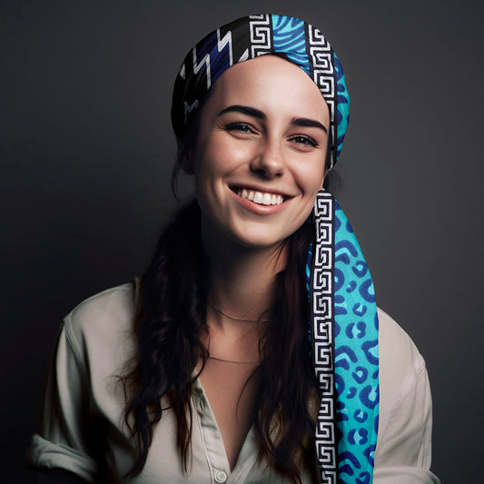 Woman wearing blue and black African print headwrap with geometric and animal patterns, styled for curly and natural hair.
