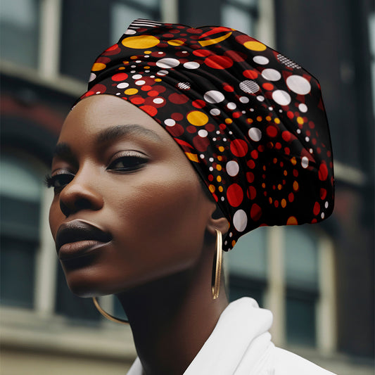 Woman wearing red and orange African print headwrap with bold circular patterns, styled for natural and curly hair.